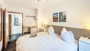 Una camera d'albergo con un letto, comodini, una scrivania e una piccola cucina sullo sfondo.