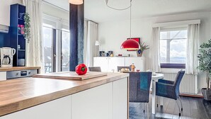 Una cucina moderna con un piano di lavoro in legno, un peperone rosso e un'area pranzo con tavolo e sedie.