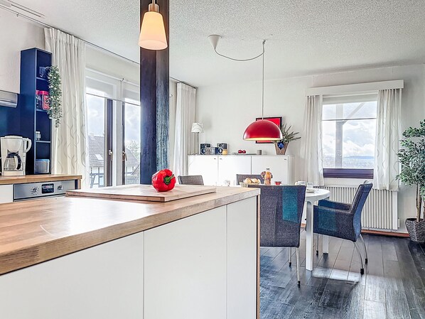Une cuisine moderne avec un plan de travail en bois, un poivron rouge et un coin repas comprenant une table et des chaises.