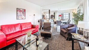 Un soggiorno moderno con un divano rosso, un tavolino in vetro e un'area pranzo con sedie e tavolo.
