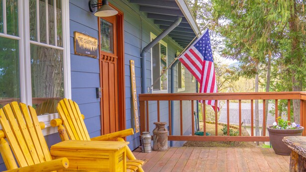 A porch with yellow Adirondack chairs, a wooden bench, a large potted plant, and an American flag. - Pet friendly w/dog run, country living & mountain views close to town with wifi (Springfield)