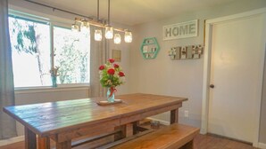 A wooden dining table with benches, a vase of red flowers, and a 'HOME' sign on the wall. - Pet friendly w/dog run, country living & mountain views close to town with wifi (Springfield)