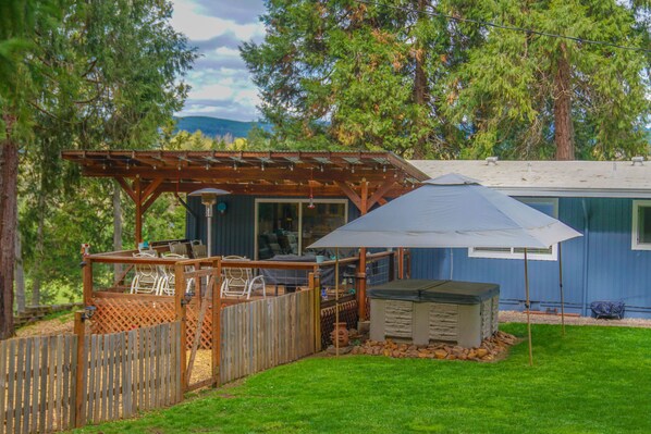Un jardin avec une terrasse en bois, un espace salon abrité et un petit abri de jardin.