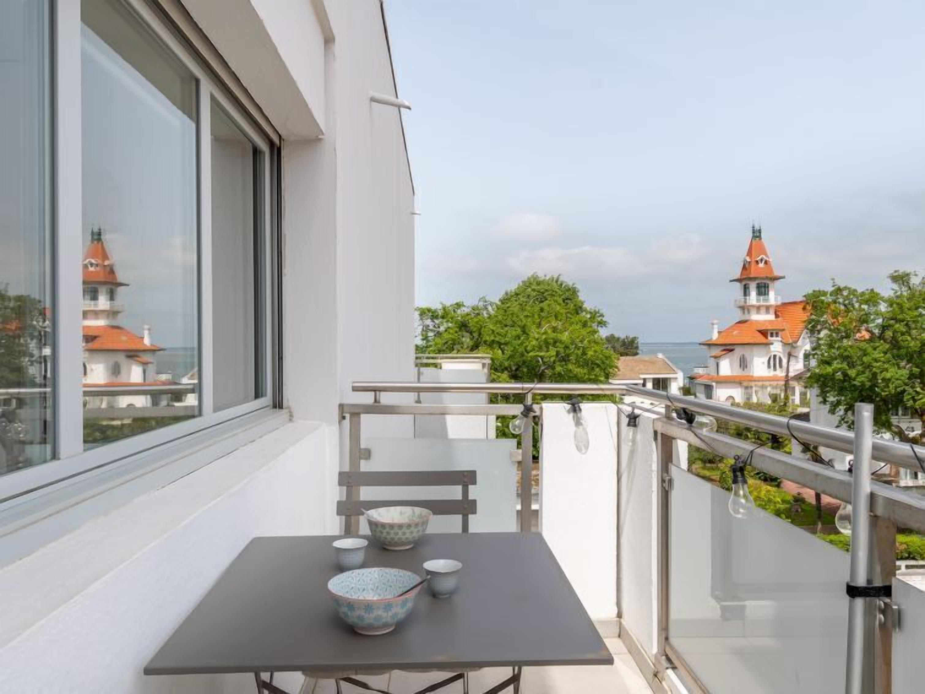 Un balcon avec une table, des chaises et une vue sur des bâtiments aux toits rouges.