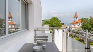 Ein Balkon mit Tisch, Stühlen und Blick auf Häuser mit roten Dächern.