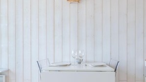 Ein weißer Esstisch mit zwei Gläsern und einer Tasse vor einer weißen Holzwand.
