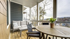 A covered outdoor seating area with a wooden table and chairs, a cushioned bench, and a potted plant. - Northshore Chattanooga - Hot Tub - Walk to Dining, Publix & Coolidge Park (Chattanooga)