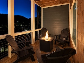 An outdoor seating area with a fire feature and two Adirondack chairs.