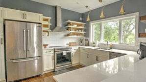 A modern kitchen with white cabinetry, stainless steel appliances, and a large window providing natural light. - Northshore Chattanooga - Hot Tub - Walk to Dining, Publix & Coolidge Park (Chattanooga)