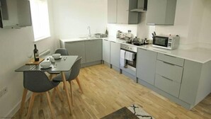 A compact kitchen with grey cabinets, a microwave, and a dining area with a table and chairs.