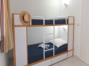 Uma cama beliche com estrutura de madeira, um colchão azul e um chapéu de palha em cima.