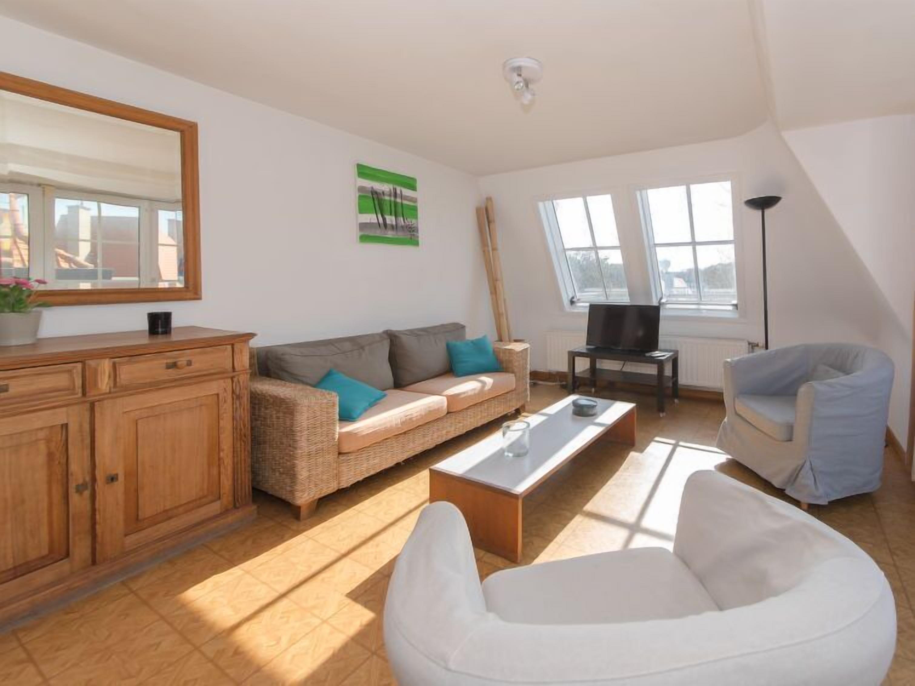 A modern living room with a sofa, a white chair, a coffee table, and a TV.