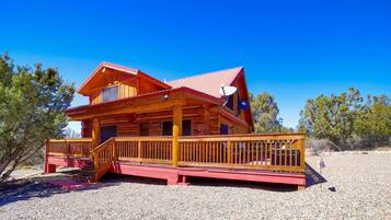 Situated in a natural setting, this cabin features a log-style building with a red roof and a wooden deck.