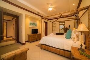 A spacious bedroom with a large bed, a television, a ceiling fan, and a bathroom visible through an open door. - Bella Vista 2D 3 bdrs pool view in Los Suenos (Playa Herradura)