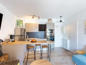 Uma cozinha moderna com uma ilha central, banquetas, micro-ondas e frigorífico.