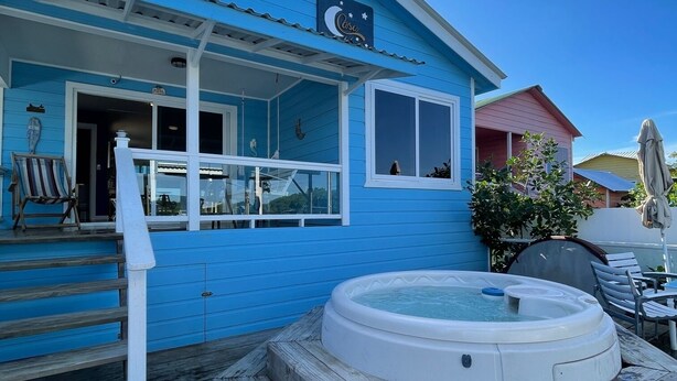 A blue house with a hot tub, wooden deck, and outdoor seating area. - Casa Moon in best neighborhood! (Utila)