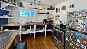 A compact kitchen with white cabinetry, a wooden countertop, and a stainless steel refrigerator adorned with travel magnets. - Casa Moon in best neighborhood! (Utila)