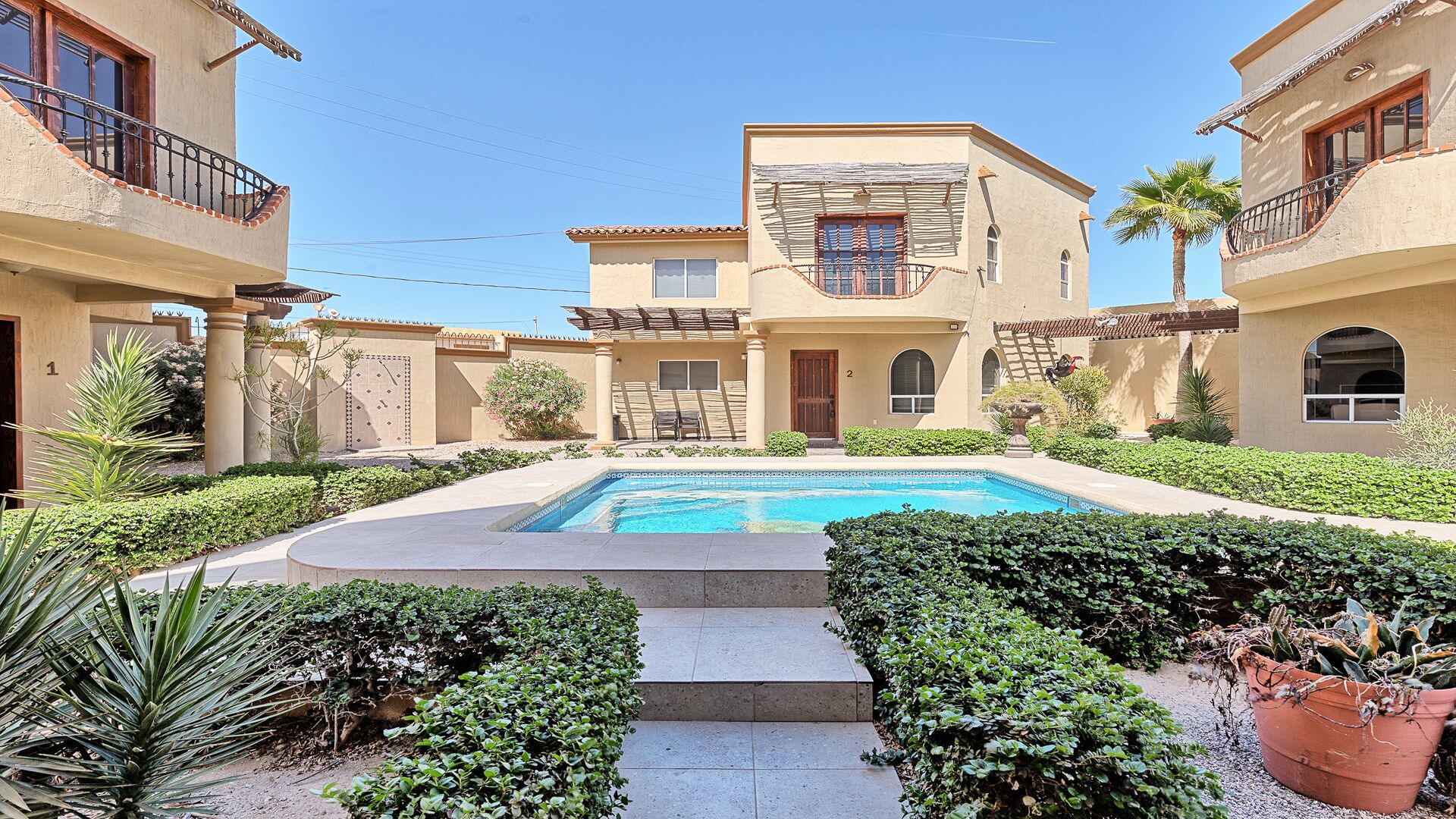 A courtyard with a swimming pool, surrounded by well-maintained hedges and plants.