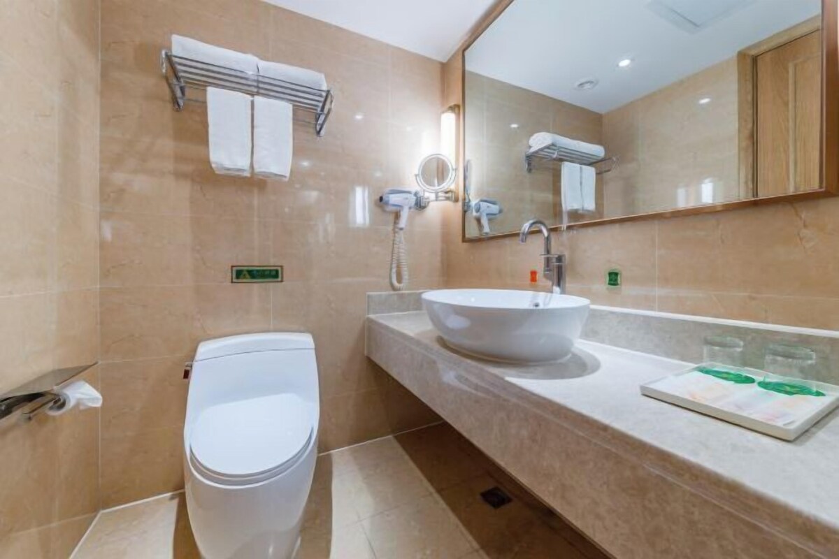 A modern bathroom with a white toilet, a sink with a mirror, and a towel rack.