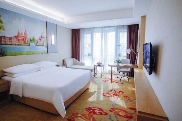 A hotel room with a large bed, a desk, a chair, a TV, and a painting on the wall.
