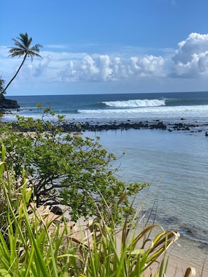 A beach with clear water, waves, and rocky shore.