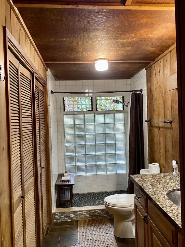 Une salle de bain avec un plafond en bois, des toilettes, un lavabo et une fenêtre donnant sur un beau paysage.