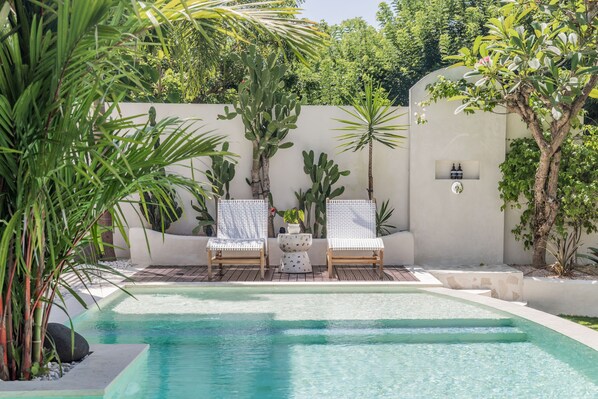 Relax by the pool surrounded by lush tropical plants and comfortable lounge chairs.