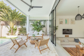 Relax in a serene space with a comfortable seating area, neutral-toned sofa, and large flat-screen TV.