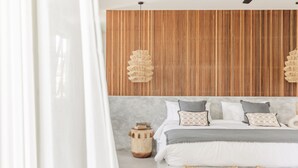 Un dormitorio moderno con un revestimiento de listones de madera, una cama con ropa de cama gris y blanca, y mesitas de noche tejidas.