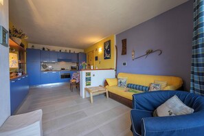 A living room with a sofa, a small table, and a kitchen in the background. - Rebecca's House (few steps from skiing) (Bardonecchia)