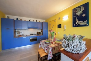 A kitchen with blue cabinets, a dining table with a floral centerpiece, and a wall-mounted artwork. - Rebecca's House (few steps from skiing) (Bardonecchia)
