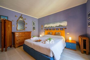 Een slaapkamer met een bed, een dressoir, een nachtkastje en een schilderij aan de muur.