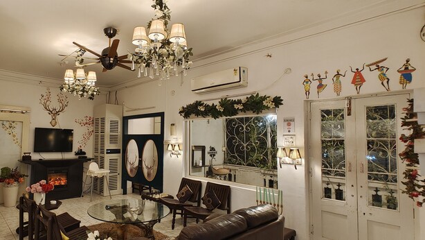 Una sala de estar con chimenea, televisor, candelabro y un espejo grande.
