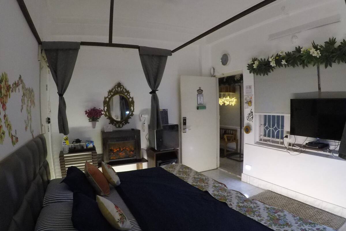 Een gezellige woonkamer met een bank, een open haard, een televisie en een deur naar een andere kamer.