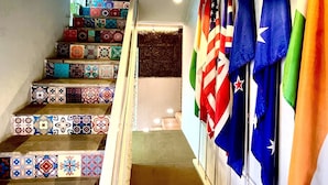 Una escalera con peldaños de colores y diseños variados que conduce a una plataforma donde se exhiben varias banderas.