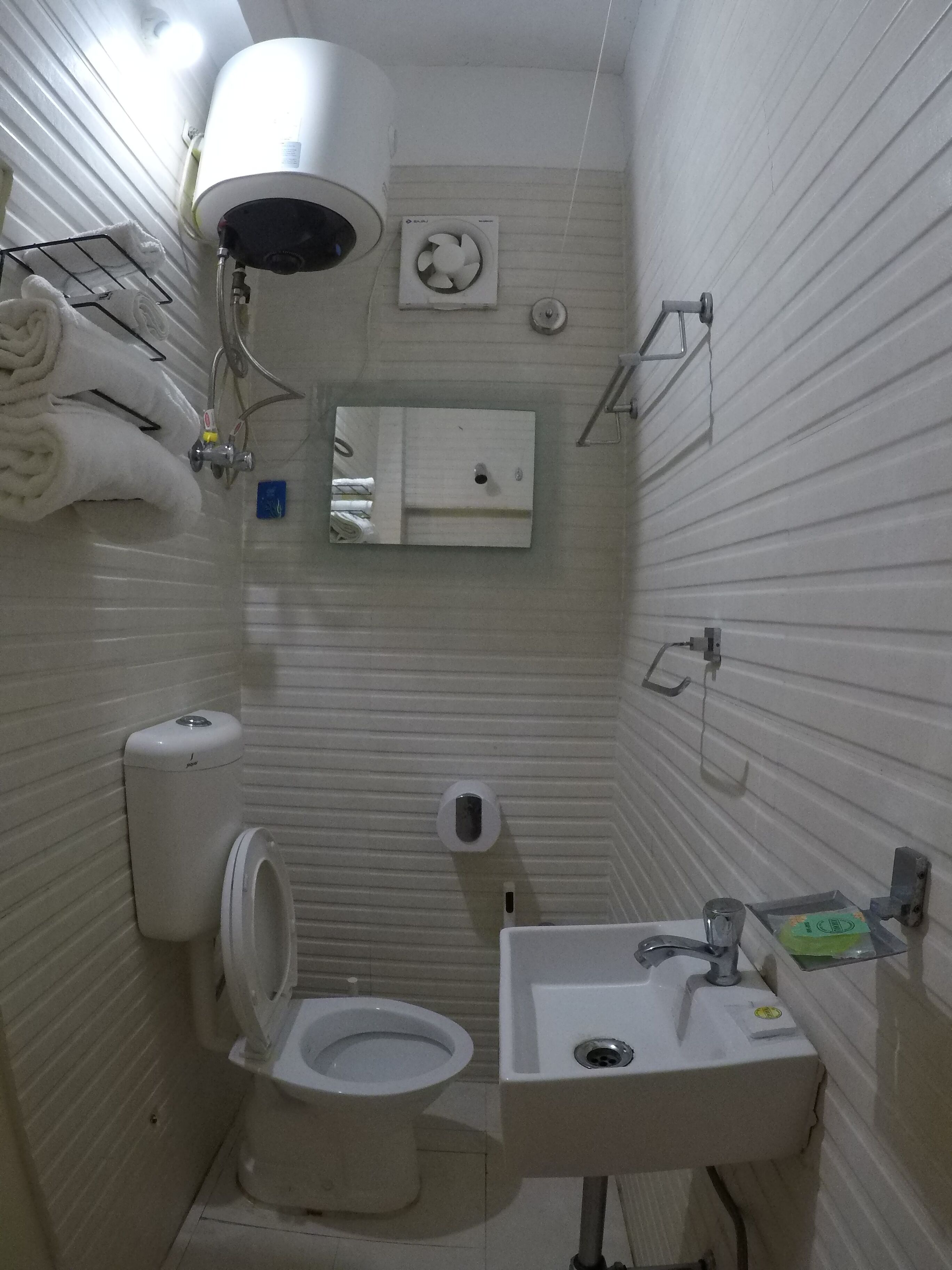 A small, compact bathroom with a toilet, sink, and a towel rack.