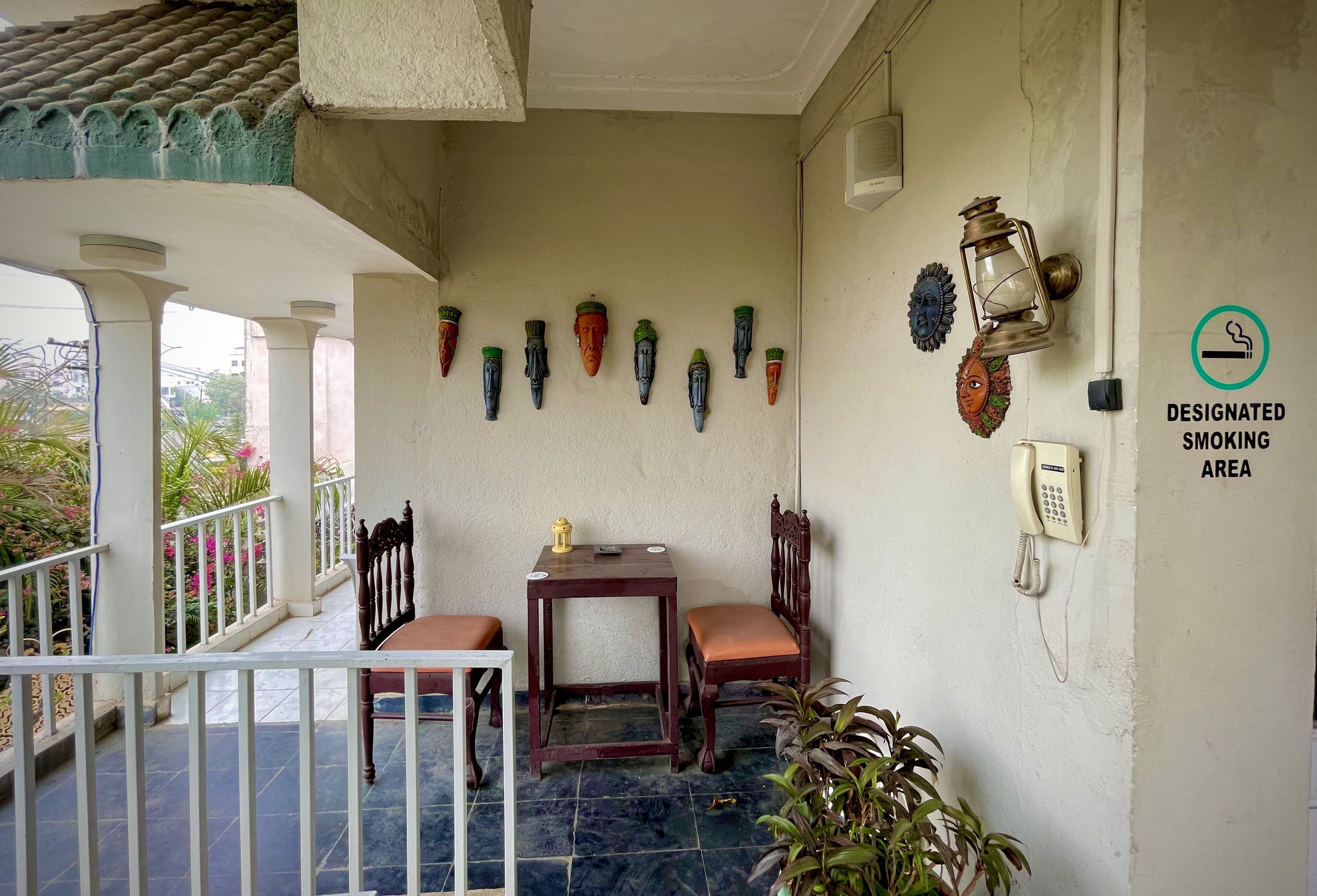 A balcony with a table and chairs, a wall-mounted telephone, and a designated smoking area sign.