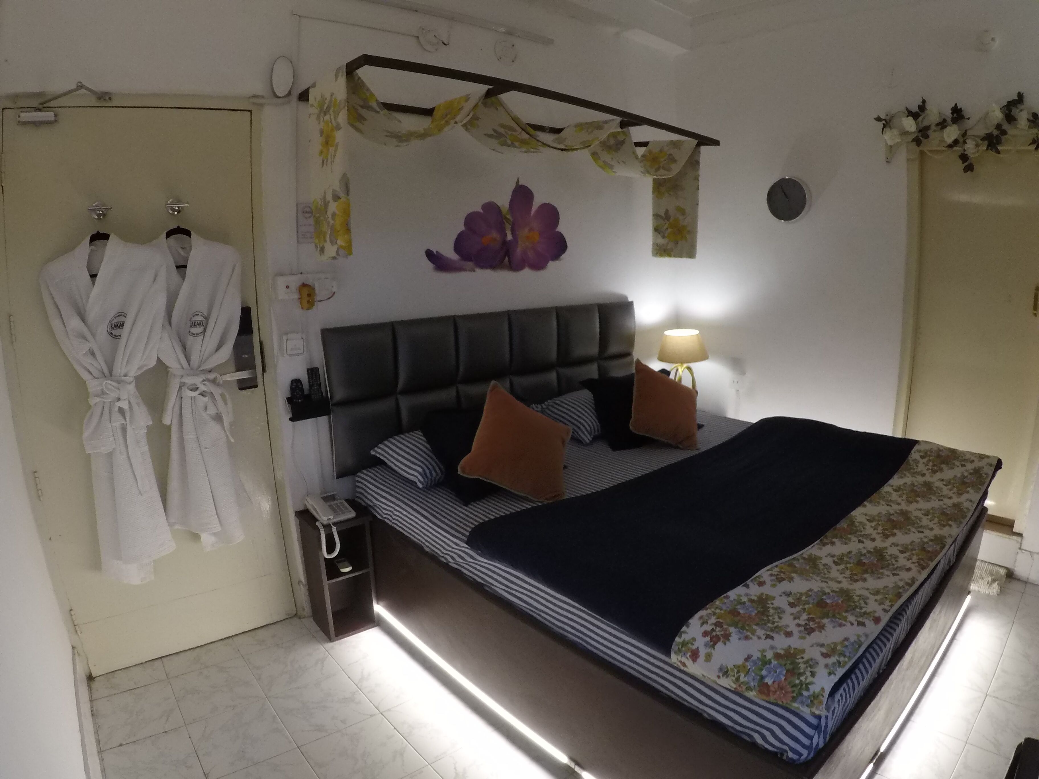 Une chambre à coucher comprenant un lit, une table de chevet, une lampe, un porte-manteau et un élément de décoration murale.