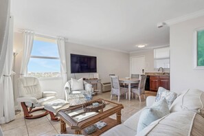 Un salon comprenant un canapé, des fauteuils, une table basse et un coin repas avec une table et des chaises.