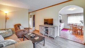 Een woonkamer met een bank, fauteuil, salontafel, tv-meubel en een eethoek met stoelen en een tafel.
