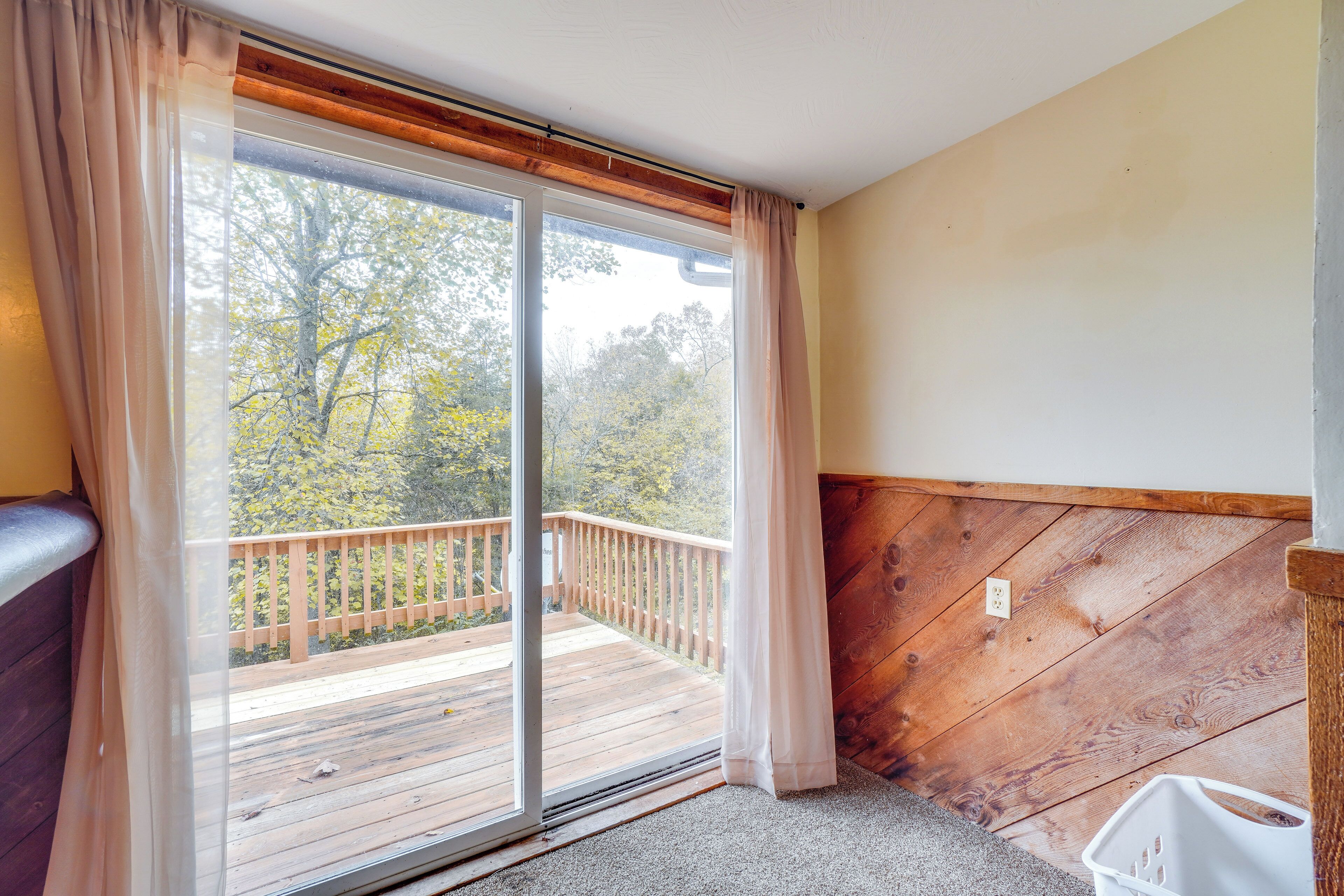 Una habitación con una puerta corrediza de vidrio que da a una terraza de madera.