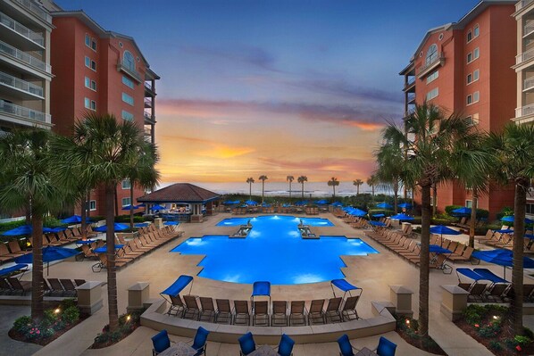 Relax by the hotel's central pool, surrounded by lounge areas and lush greenery.