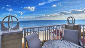 Ein Balkon mit Meerblick, ausgestattet mit zwei Stühlen und einem Tisch.