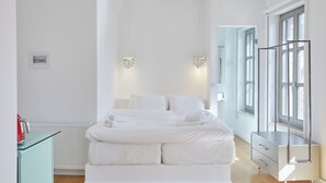 A modern bedroom with a large bed, bedside tables, and a wardrobe.