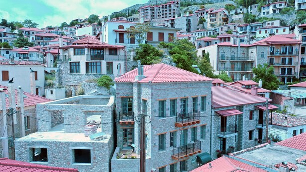 A densely packed hillside residential area with stone buildings featuring red-tiled roofs.