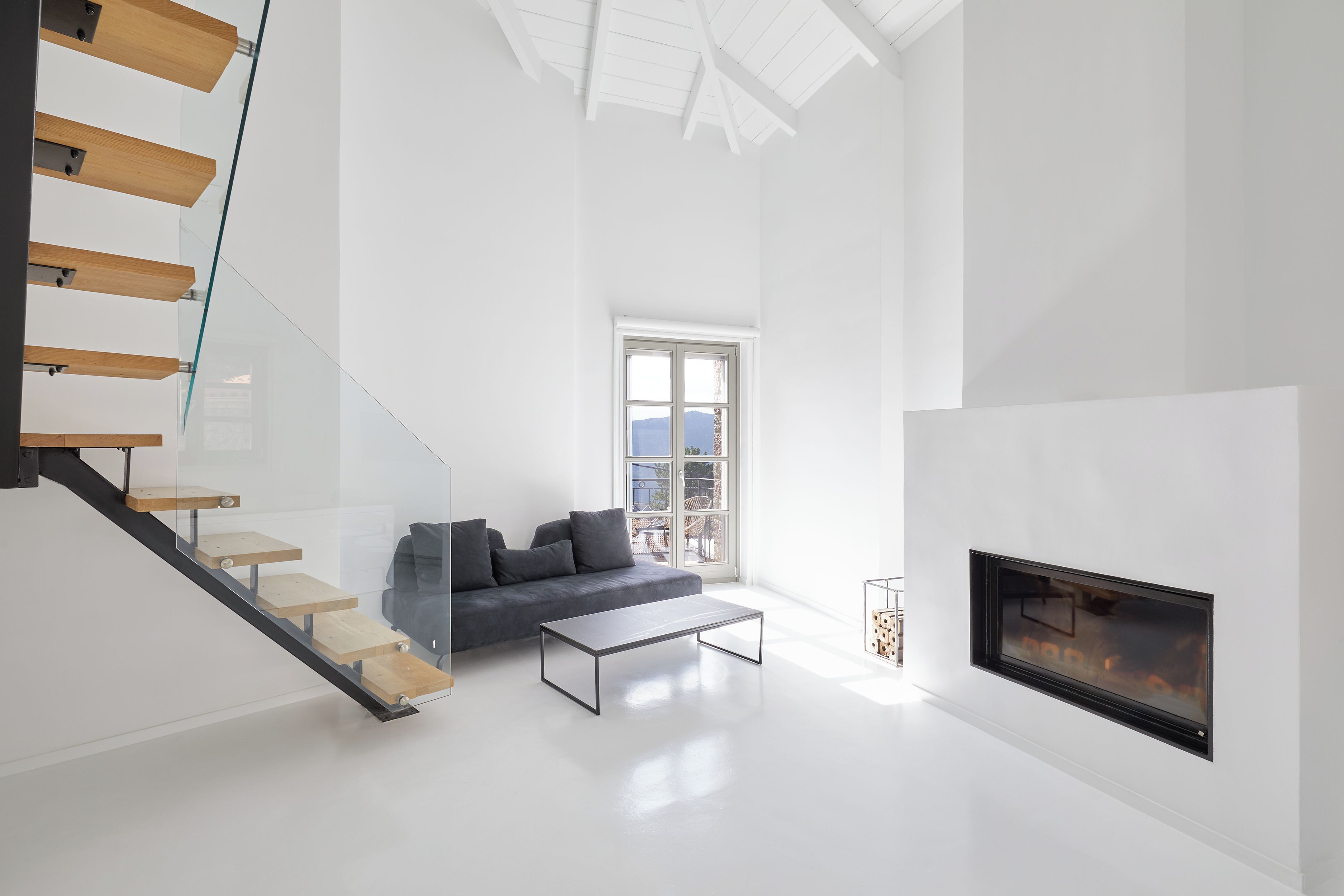 Una sala de estar moderna con una escalera, un sofá, una mesa de centro y una chimenea.