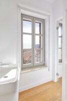 Un baño con ventana, lavamanos y suelo de madera.