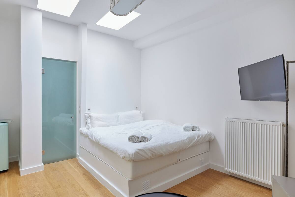 Une chambre moderne avec un lit, une télévision et un radiateur.