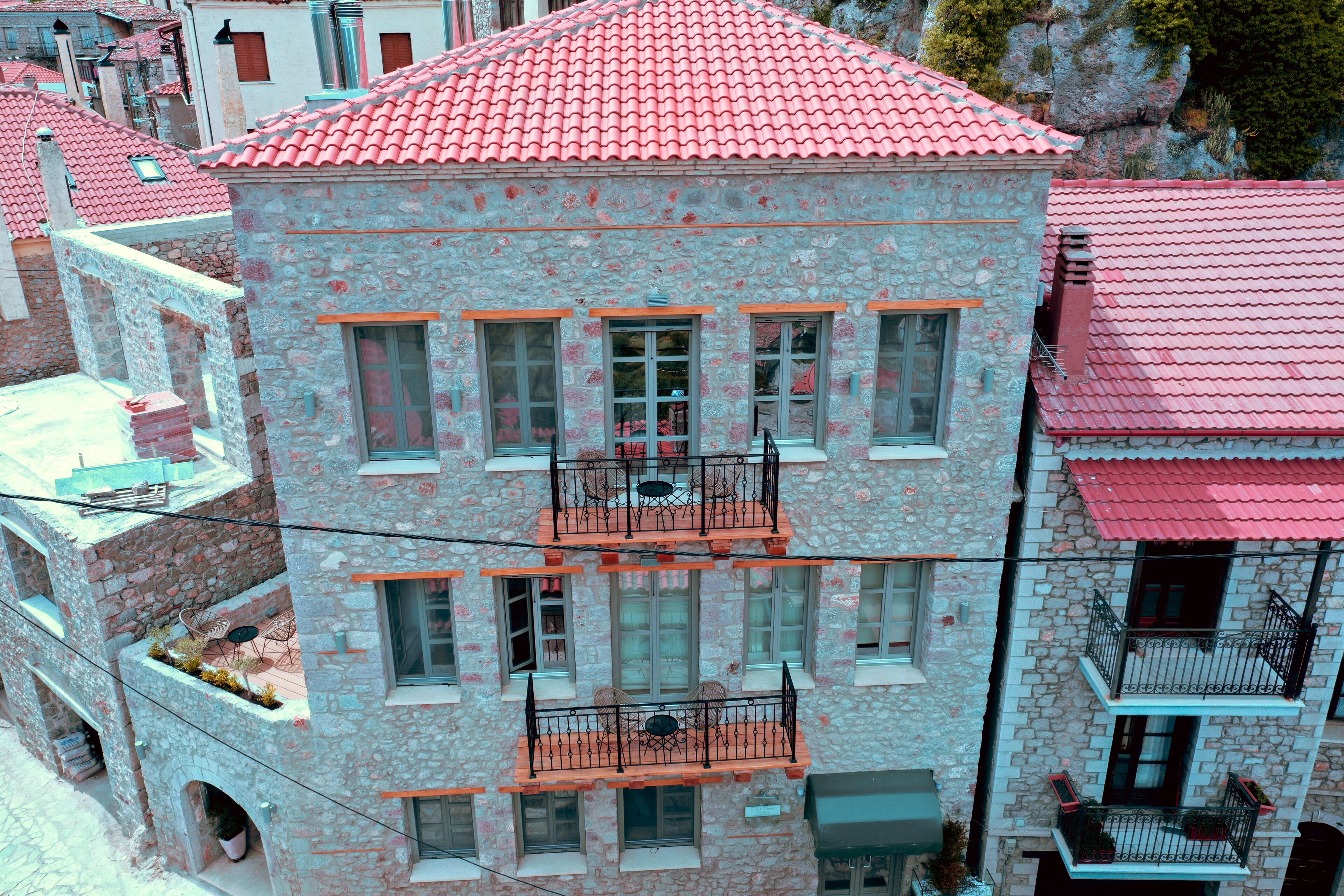 Un edificio de varios pisos de piedra con balcones, tejados de tejas rojas y fachada de piedra.