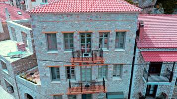 Un edificio de varios pisos de piedra con balcones, tejados de tejas rojas y fachada de piedra.